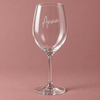 Weinglas mit Name Anna vor roséfarbenem Hintergrund